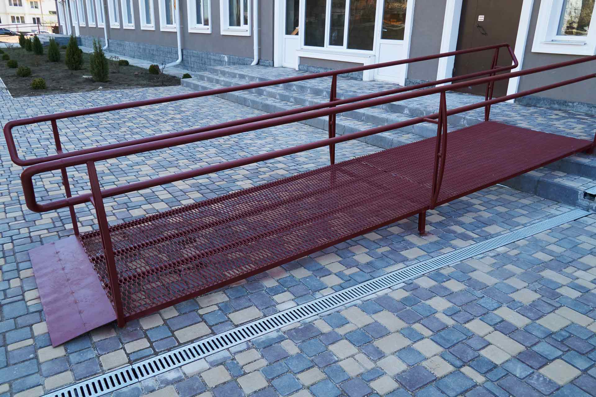 A red ramp is sitting on a brick sidewalk in front of a building.