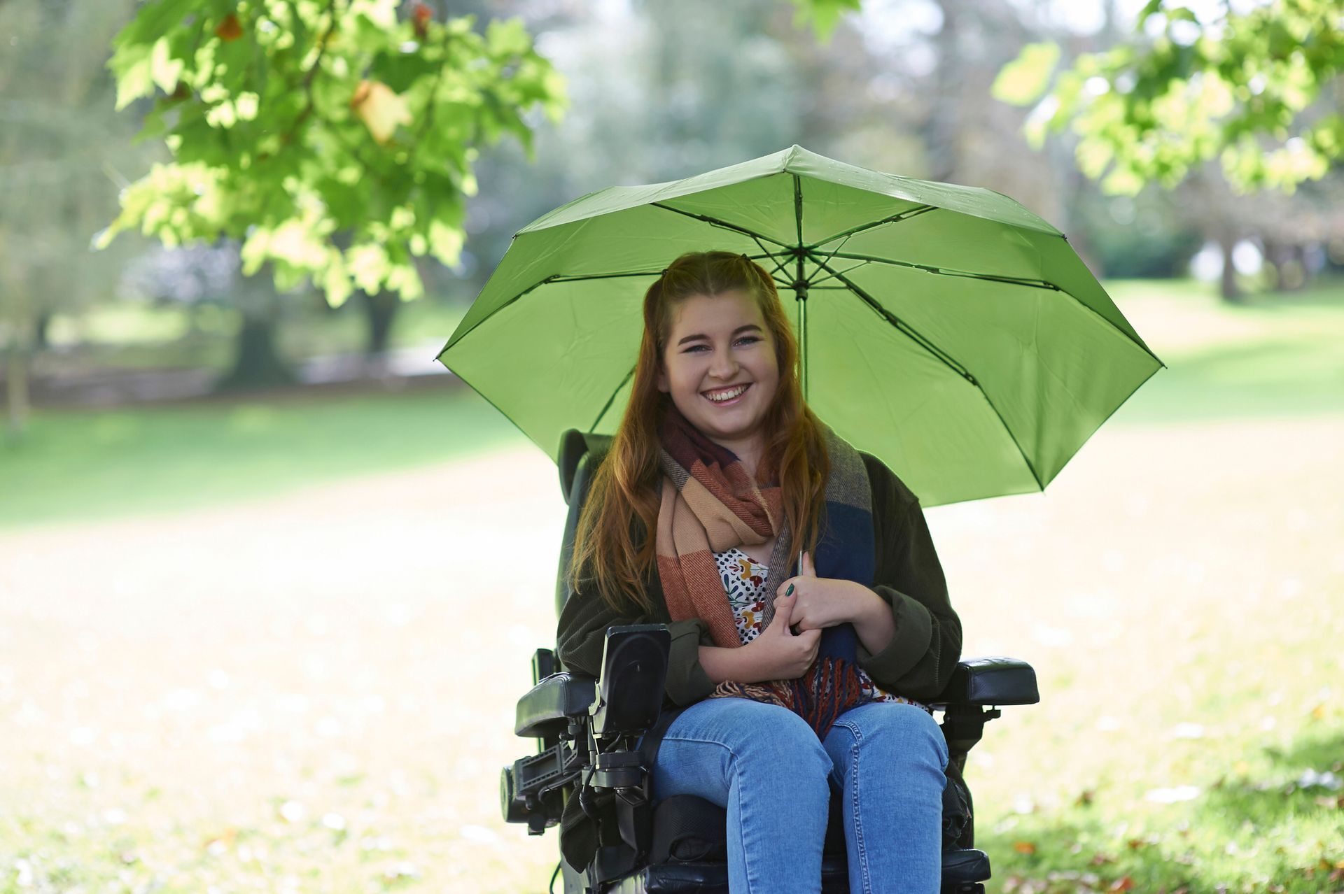A woman in a wheelchair holding an umbrella, looking to find a motor scooter dealer for mobility.