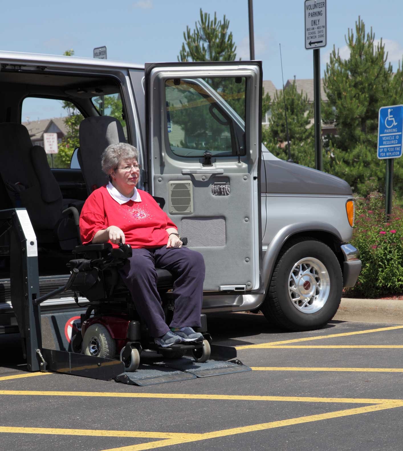 A woman in a wheelchair is sitting in a handicapped parking spot