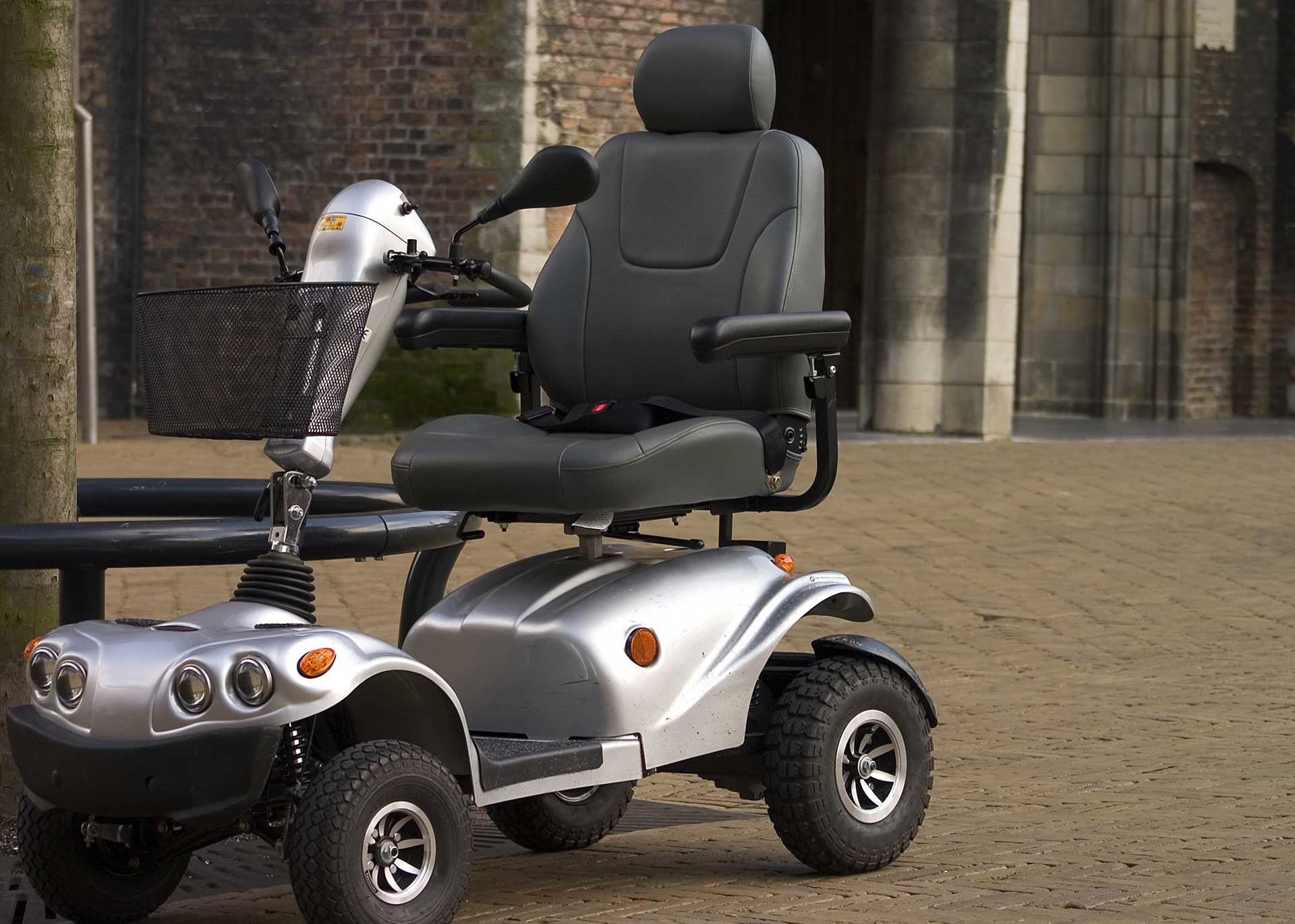 A silver mobility scooter is parked in front of a building.