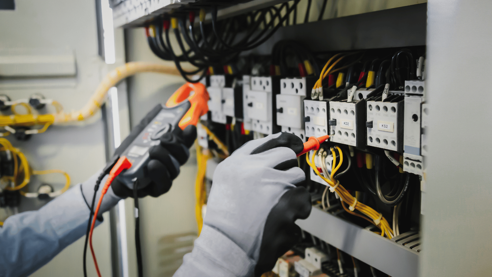 An electrician is working on an electrical box with a multimeter.