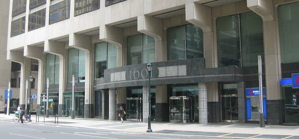 Exterior of a large building with glass windows and multiple entrances. Street-level view.