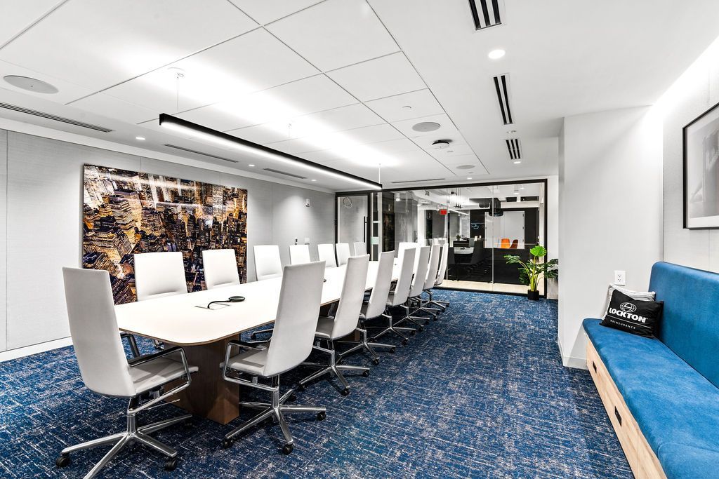 Red brick building with clock tower under a cloudy sky, set on a grassy field.