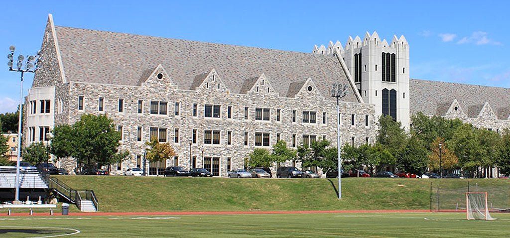Large stone building on a green field under a clear blue sky.