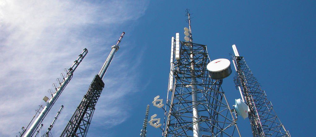 Telecommunication towers against a bright blue sky.