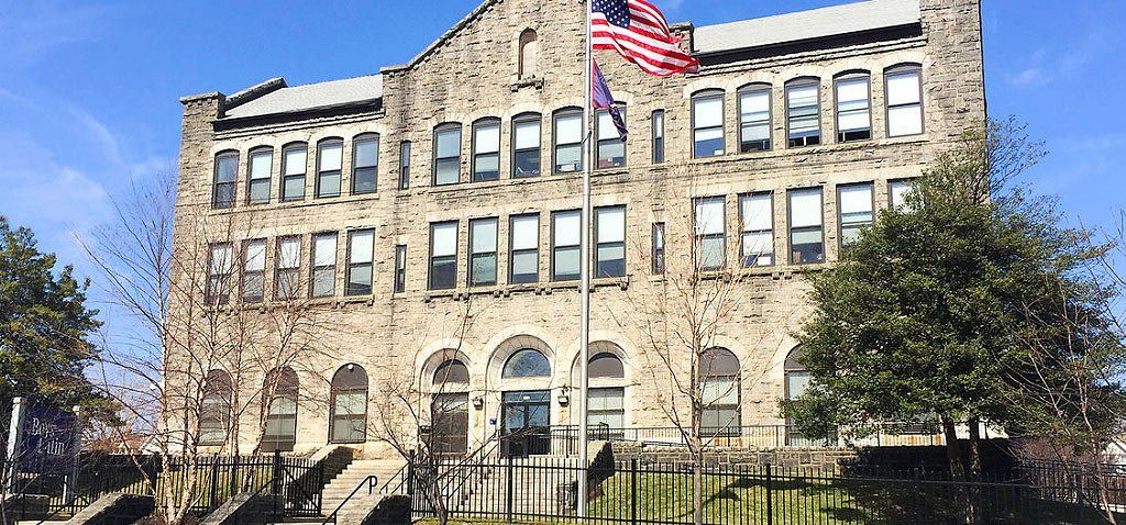 Stone building with American flag on a clear day.