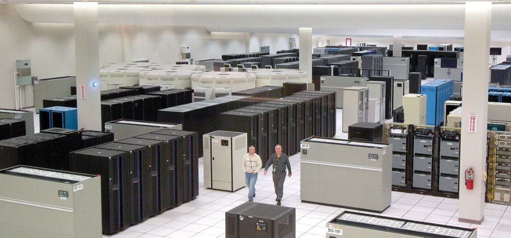 Two people walking in a data center filled with server racks.