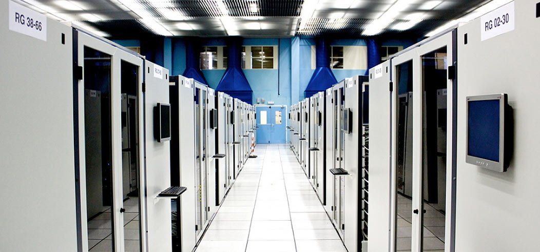 A data center hallway with server racks, blue accents, and bright lighting.
