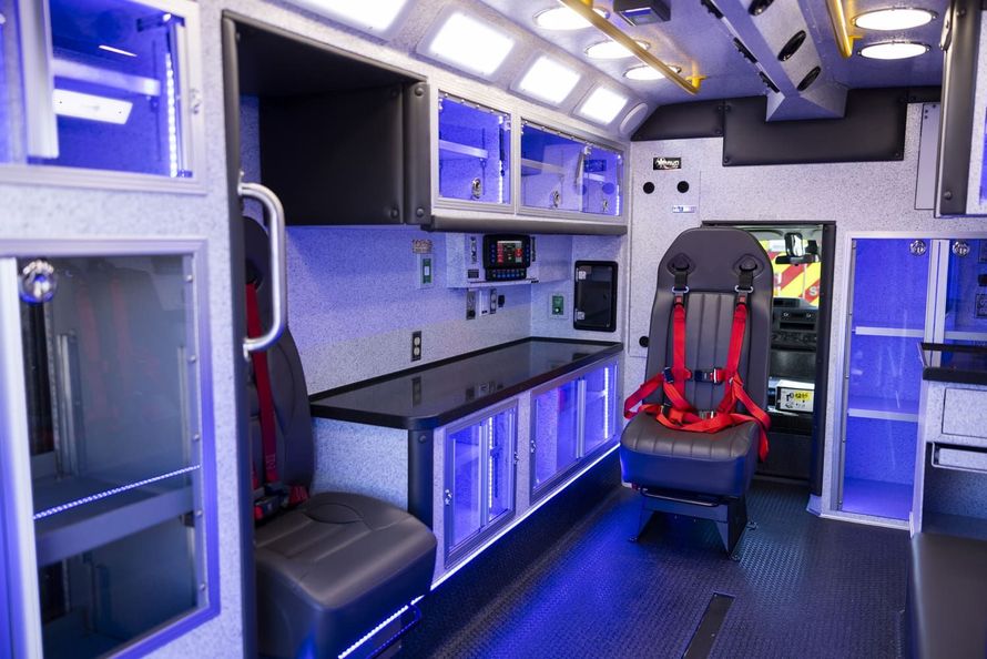 The inside of an ambulance with red seat belts.