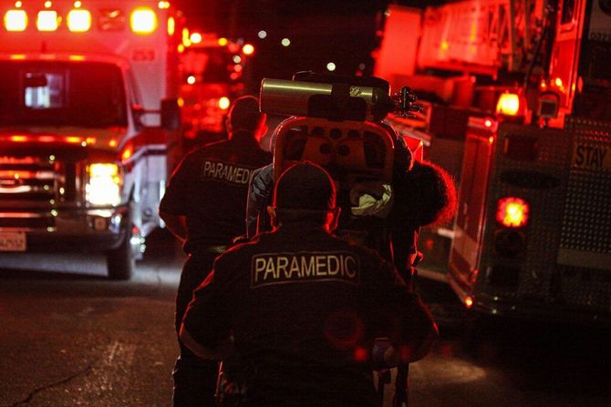 A group of paramedics are walking down a street at night.