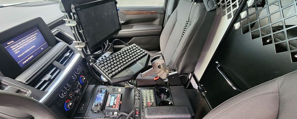The inside of a police car with a computer and keyboard.
