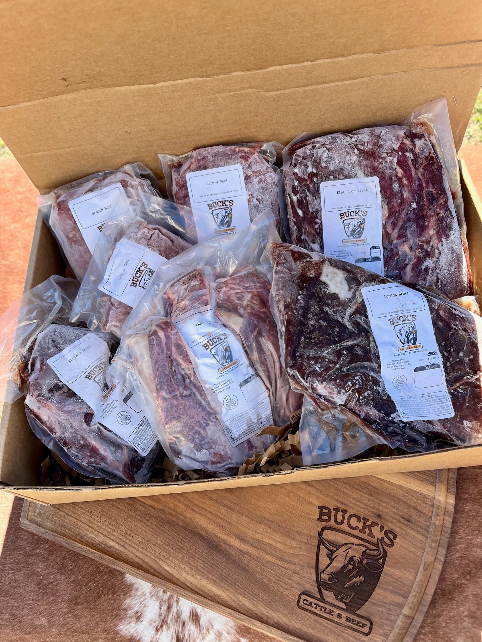 Open cardboard box filled with vacuum-sealed packages of raw meat or steaks.