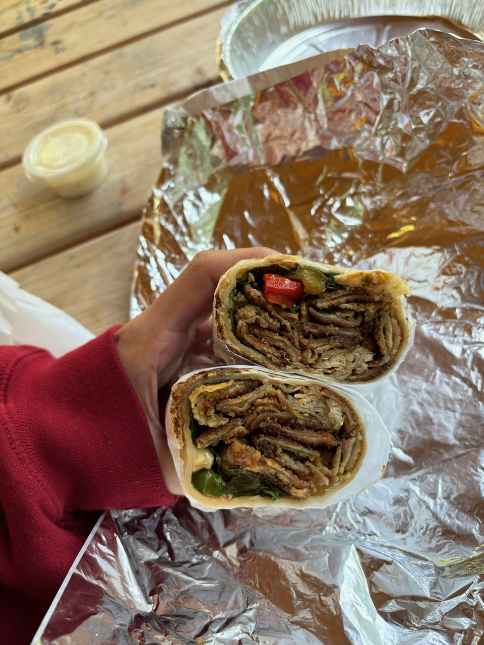 Two beers, fries, and grilled food on a basket, wooden table.
