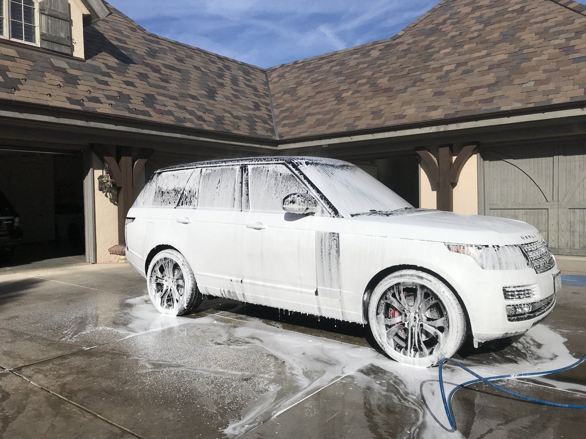 a white range rover is covered in foam in front of a house .