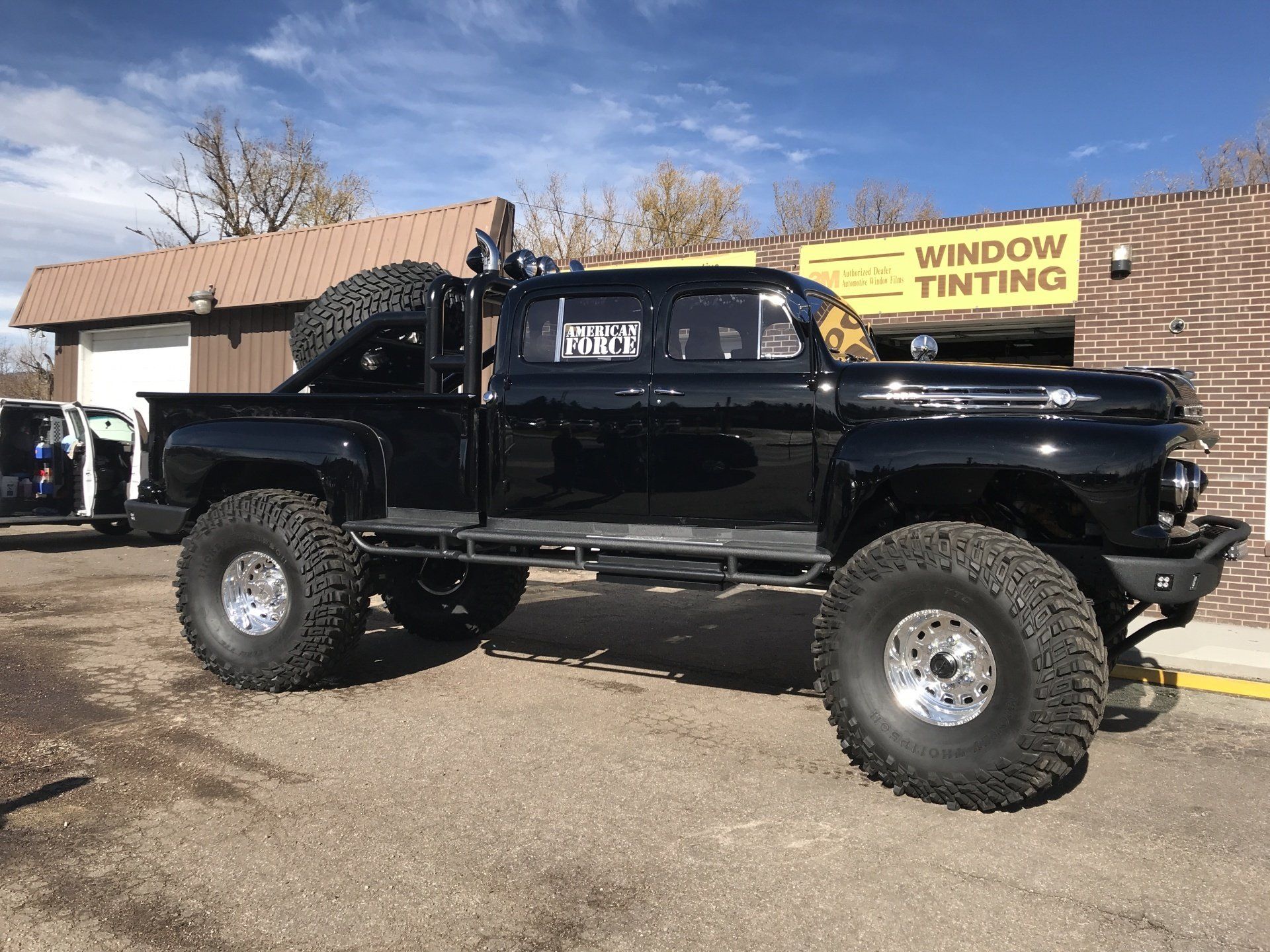 a black truck parked in front of a window tinting shop .