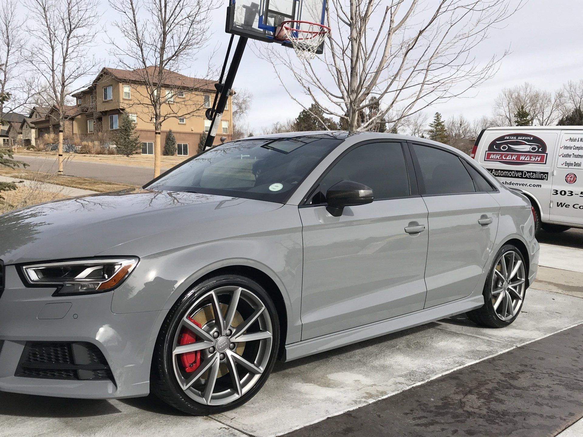 a gray car parked in a driveway next to a basketball hoop .