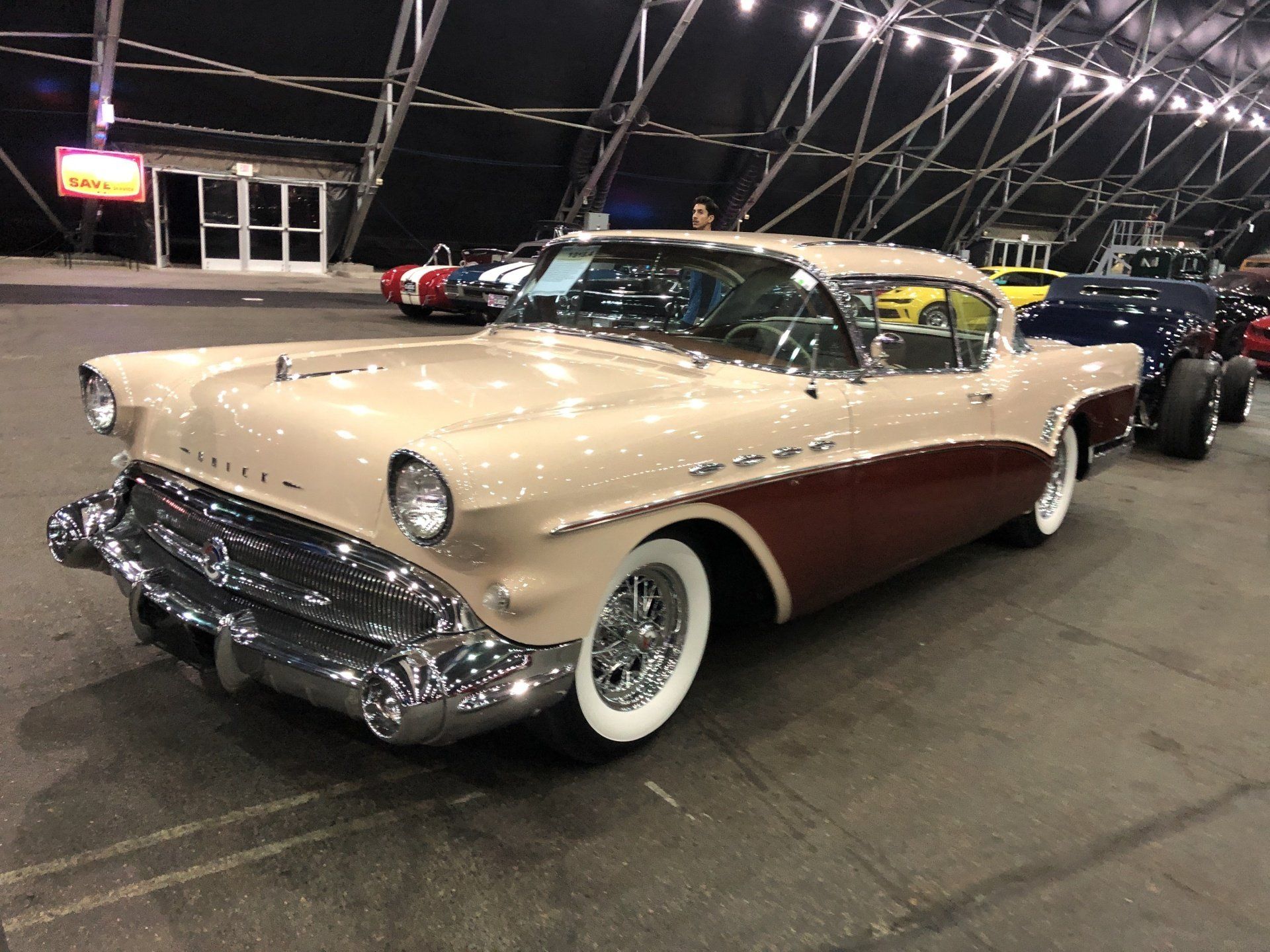 an old car parked in a garage with other cars .