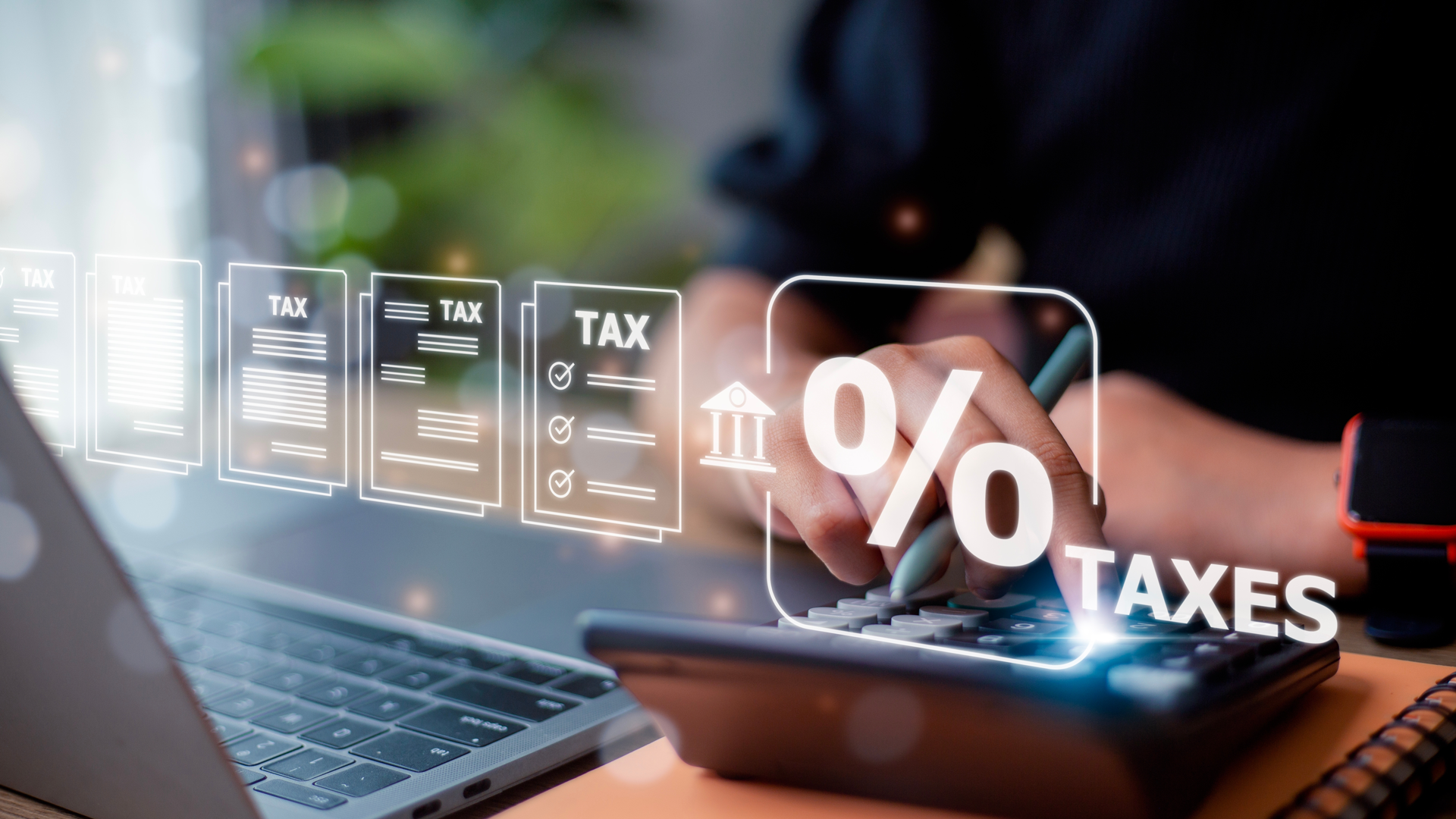 A person is using a laptop and a calculator to calculate taxes.