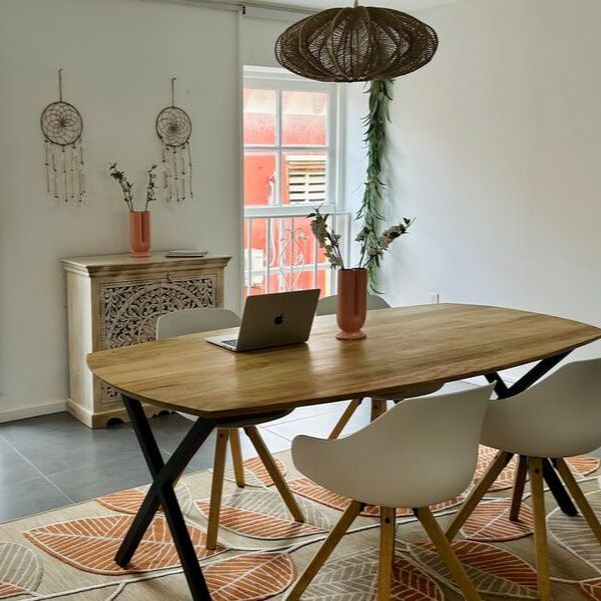 Dining room with wooden table, white chairs, rug, and decorative elements like dreamcatchers and a patterned cabinet.