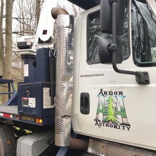 White Arbor Authority truck with tall exhaust pipe, logo visible.