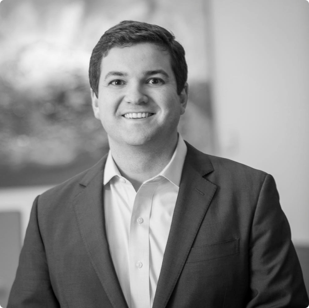A man in a suit and white shirt is smiling in a black and white photo