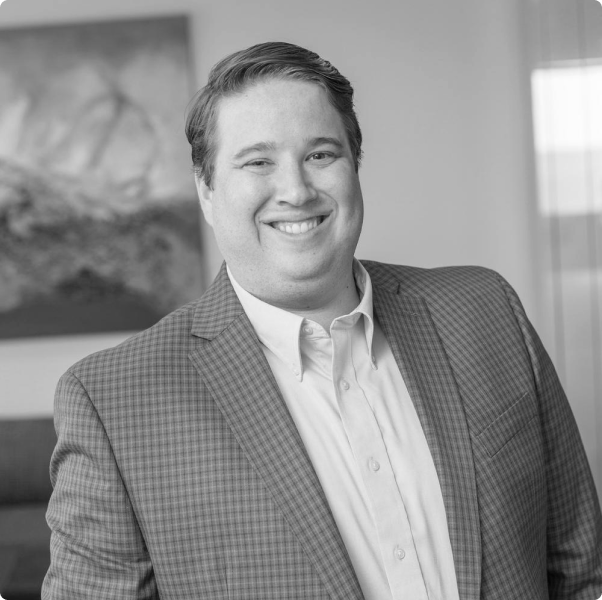 A man in a suit and white shirt is smiling in a black and white photo.