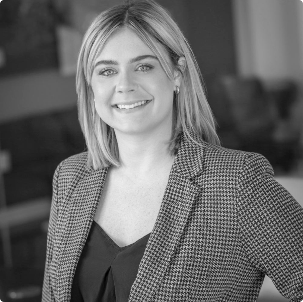 A woman in a plaid jacket is smiling in a black and white photo.