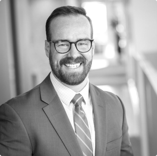 A man in a suit and tie is smiling in a black and white photo.