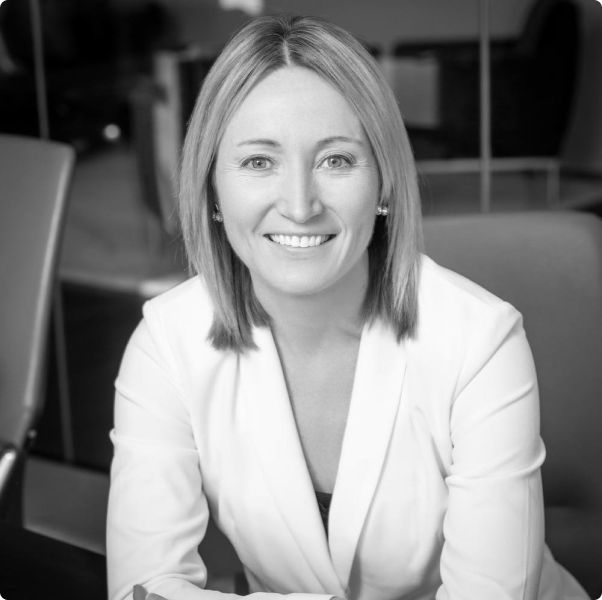 A woman in a white jacket is smiling in a black and white photo