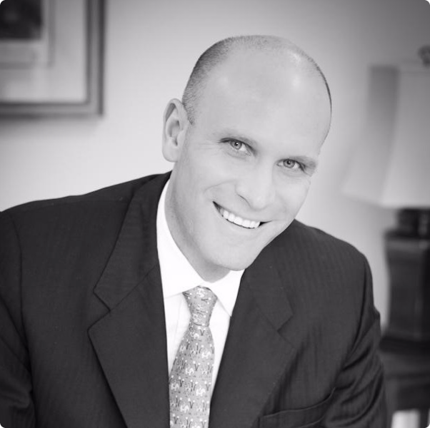 A man in a suit and tie is smiling for the camera