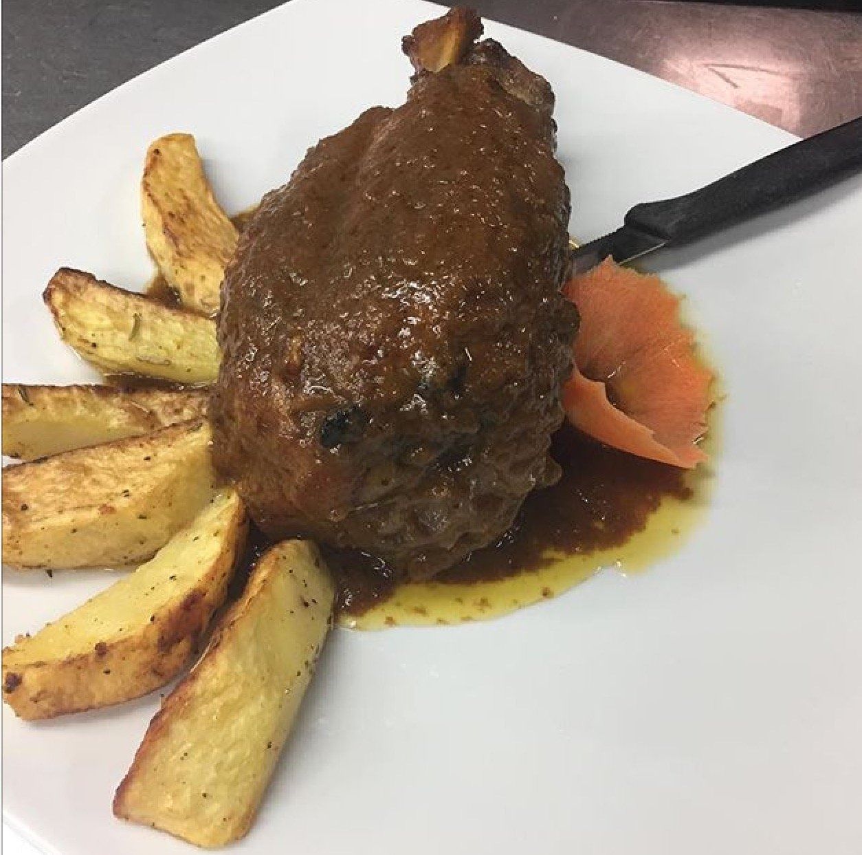 Un piatto bianco con carne e patatine fritte