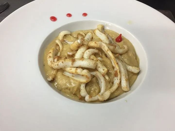 Un primo piano di un piatto di cibo con calamari in salsa