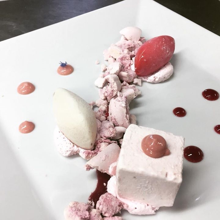 Un piatto bianco sormontato da dessert rosa e bianchi