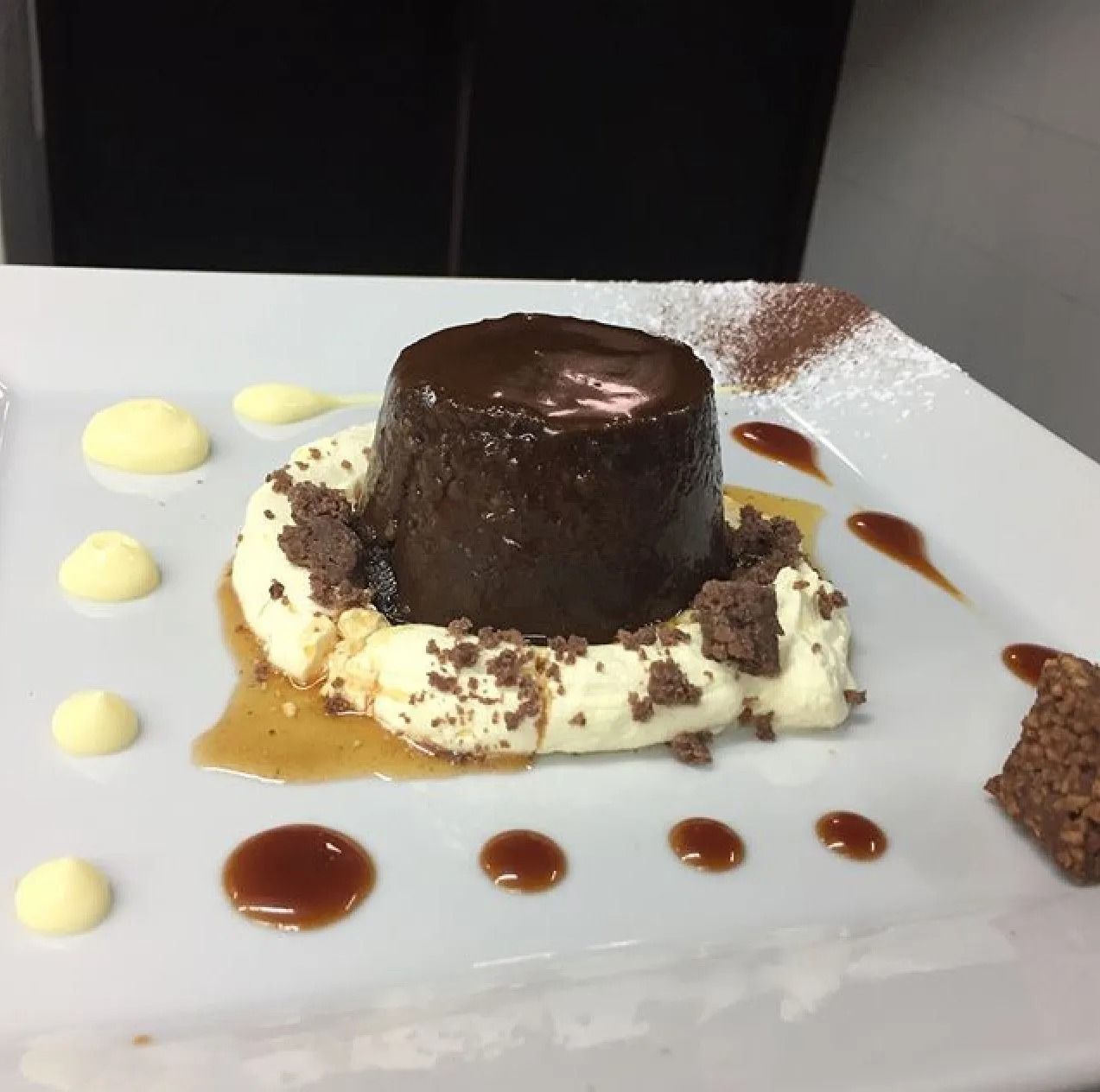 Un dessert al cioccolato con panna montata e scaglie di cioccolato su un piatto bianco