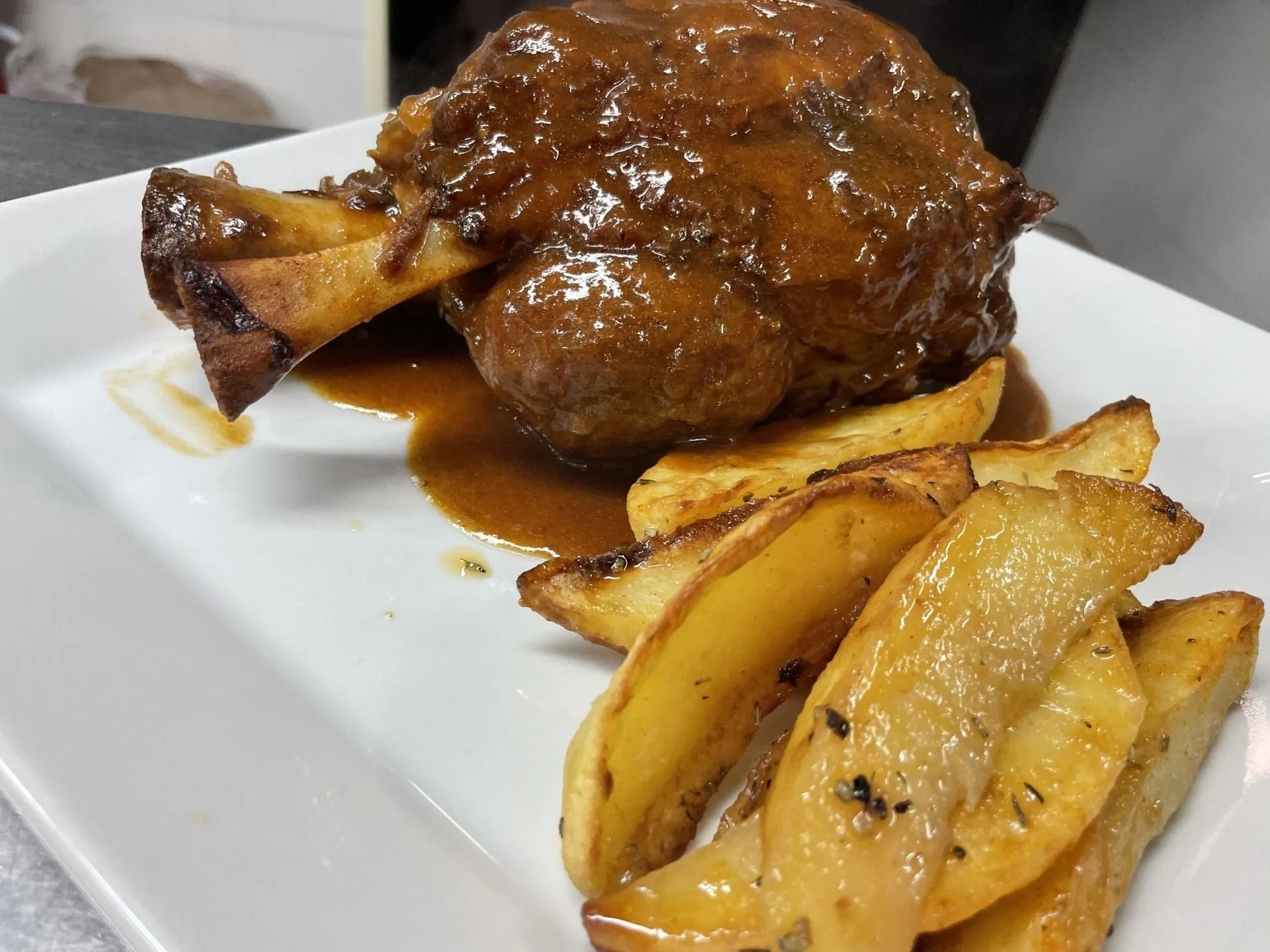 Un piatto bianco con carne e patatine fritte