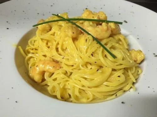 Un piatto bianco con sopra noodles e gamberetti