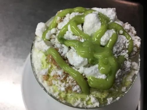 Una ciotola di cibo con salsa verde e panna montata sopra.