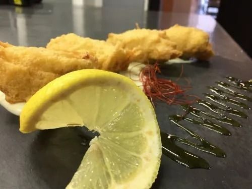 Un primo piano di un piatto di cibo con una fetta di limone su un tavolo.