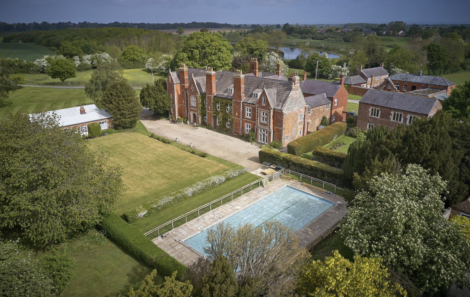 An aerial view of a large house with a swimming pool in front of it.