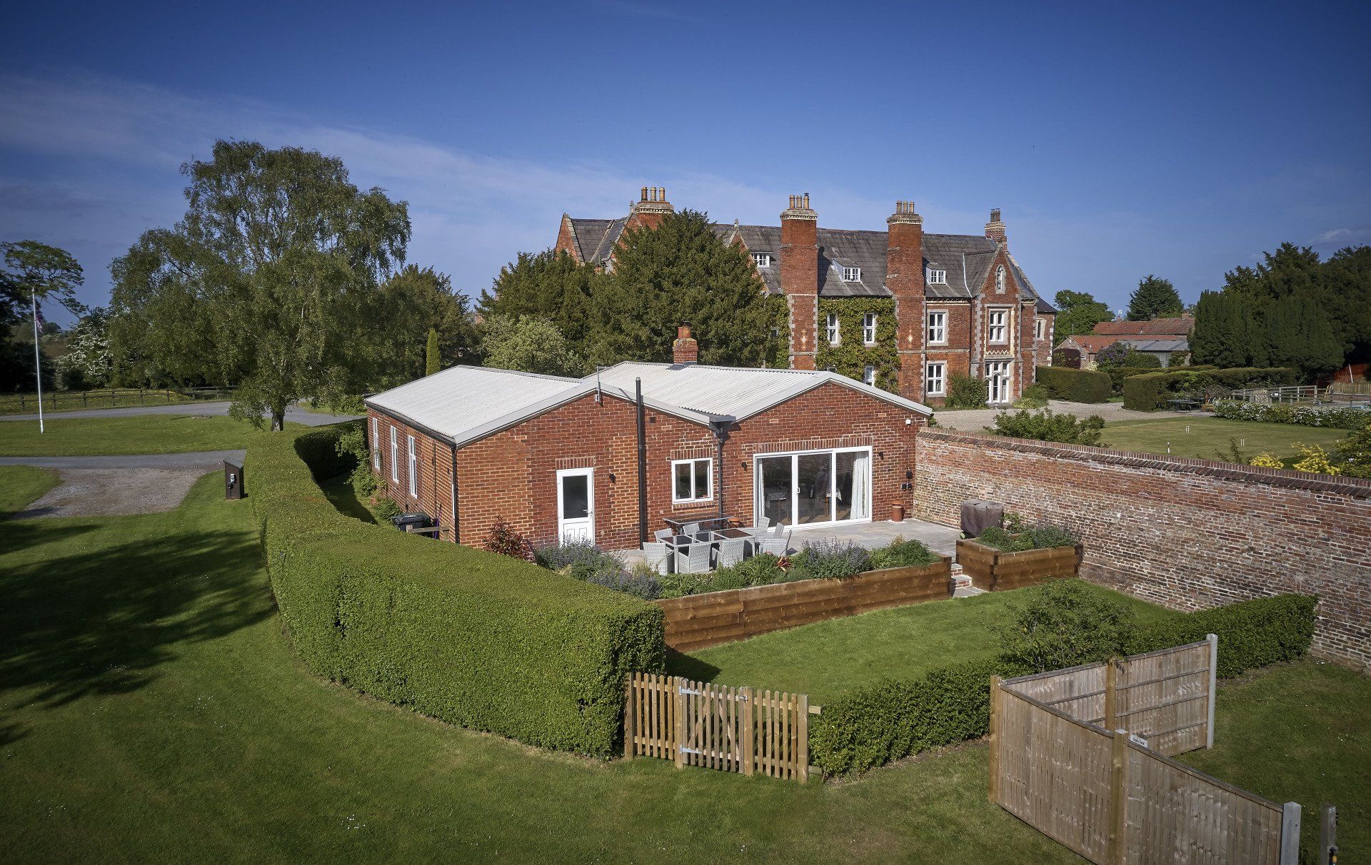 An aerial view of a brick house with a large house in the background