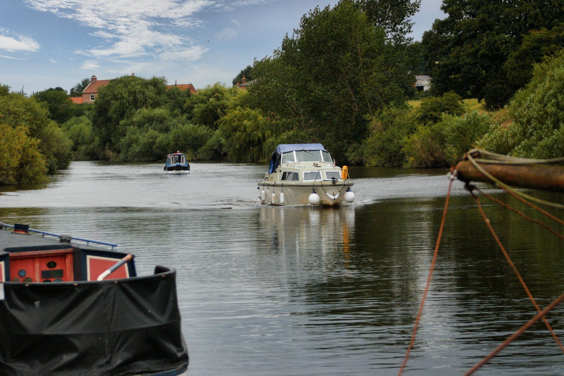 Two boats are floating on a river with trees in the background