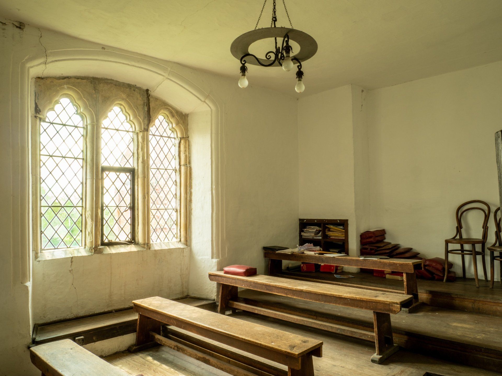 A room with a table and benches in front of a window.