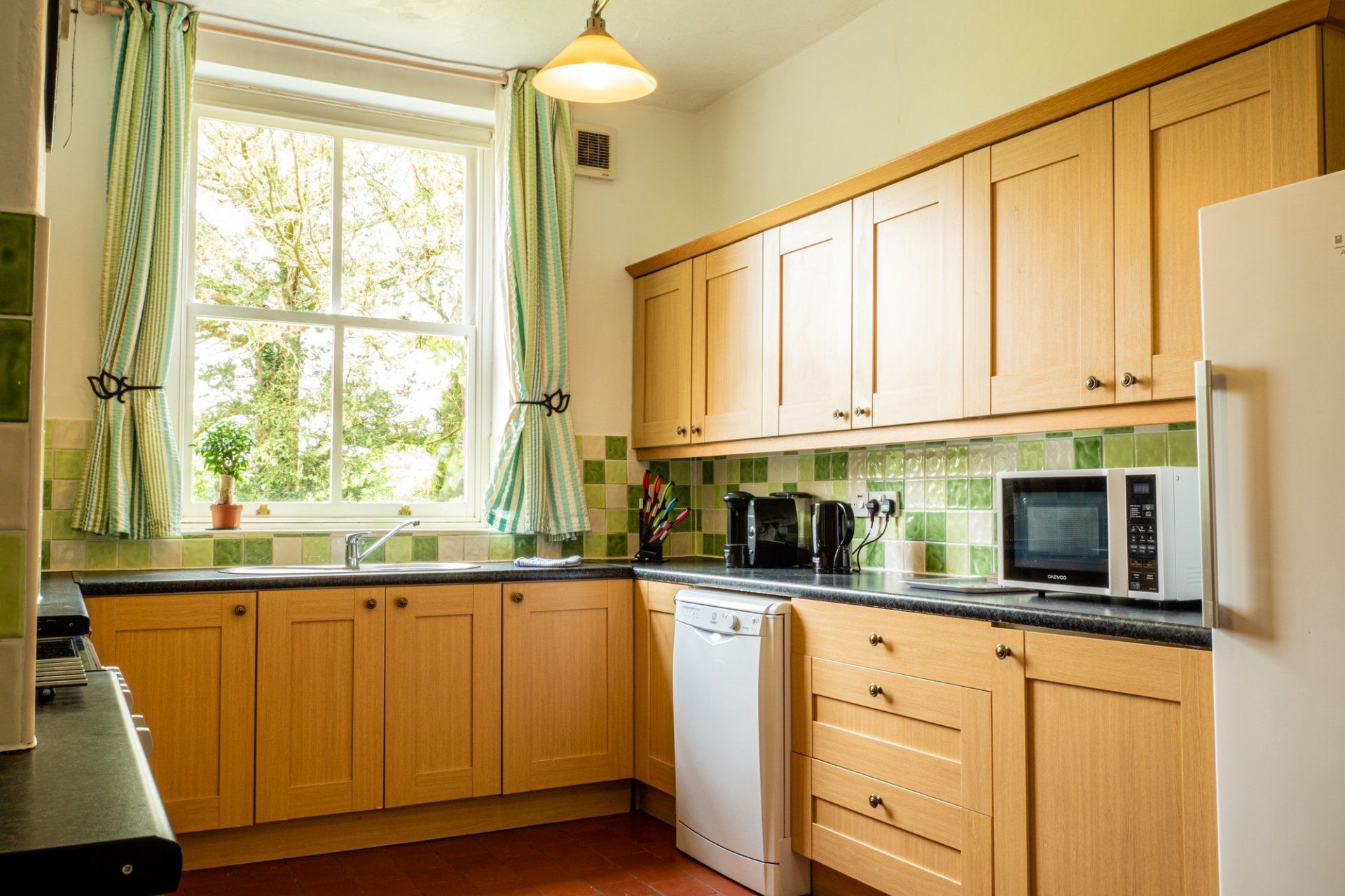 A kitchen with wooden cabinets , a refrigerator , a microwave , and a sink.