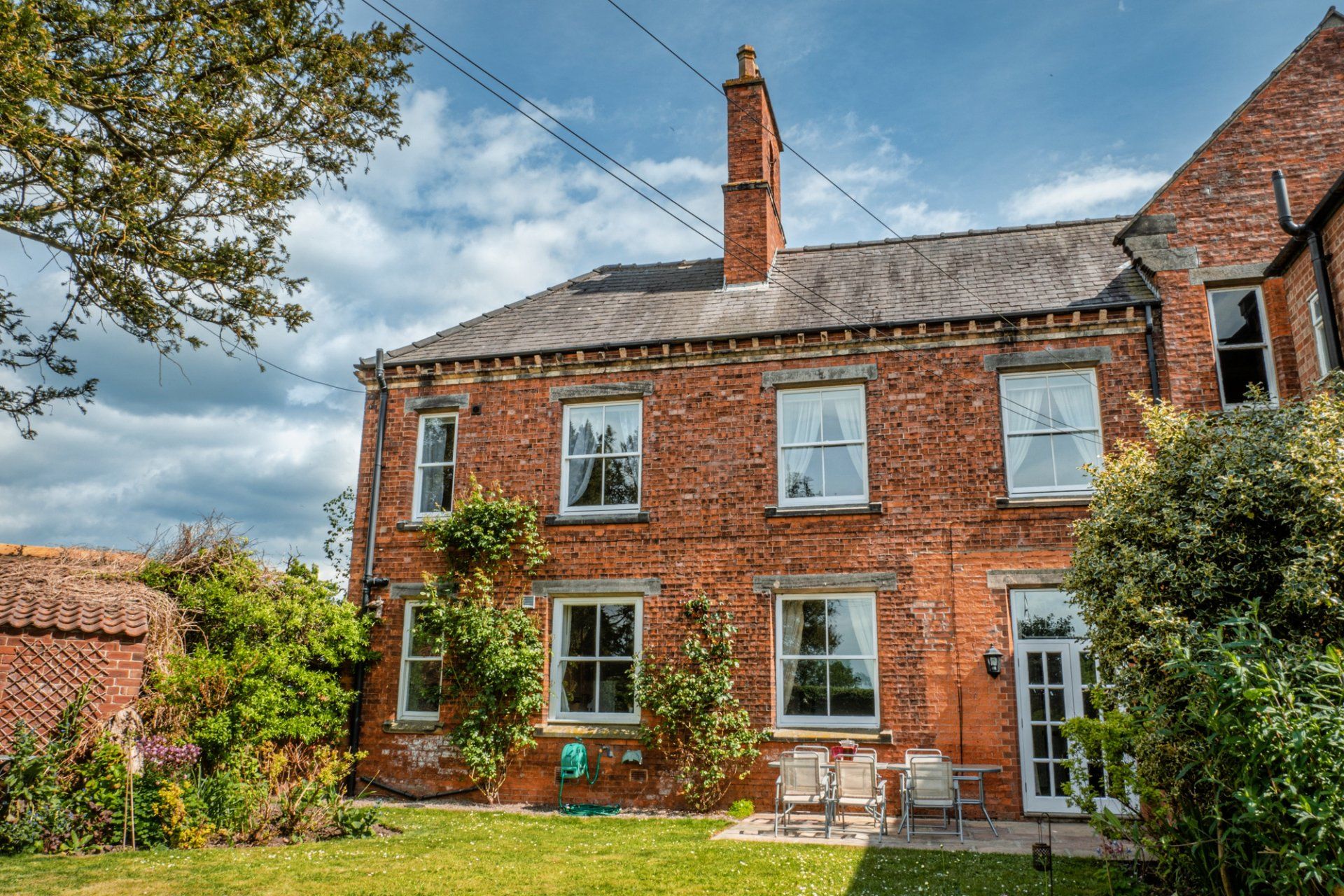 A large brick house with a large lawn in front of it.