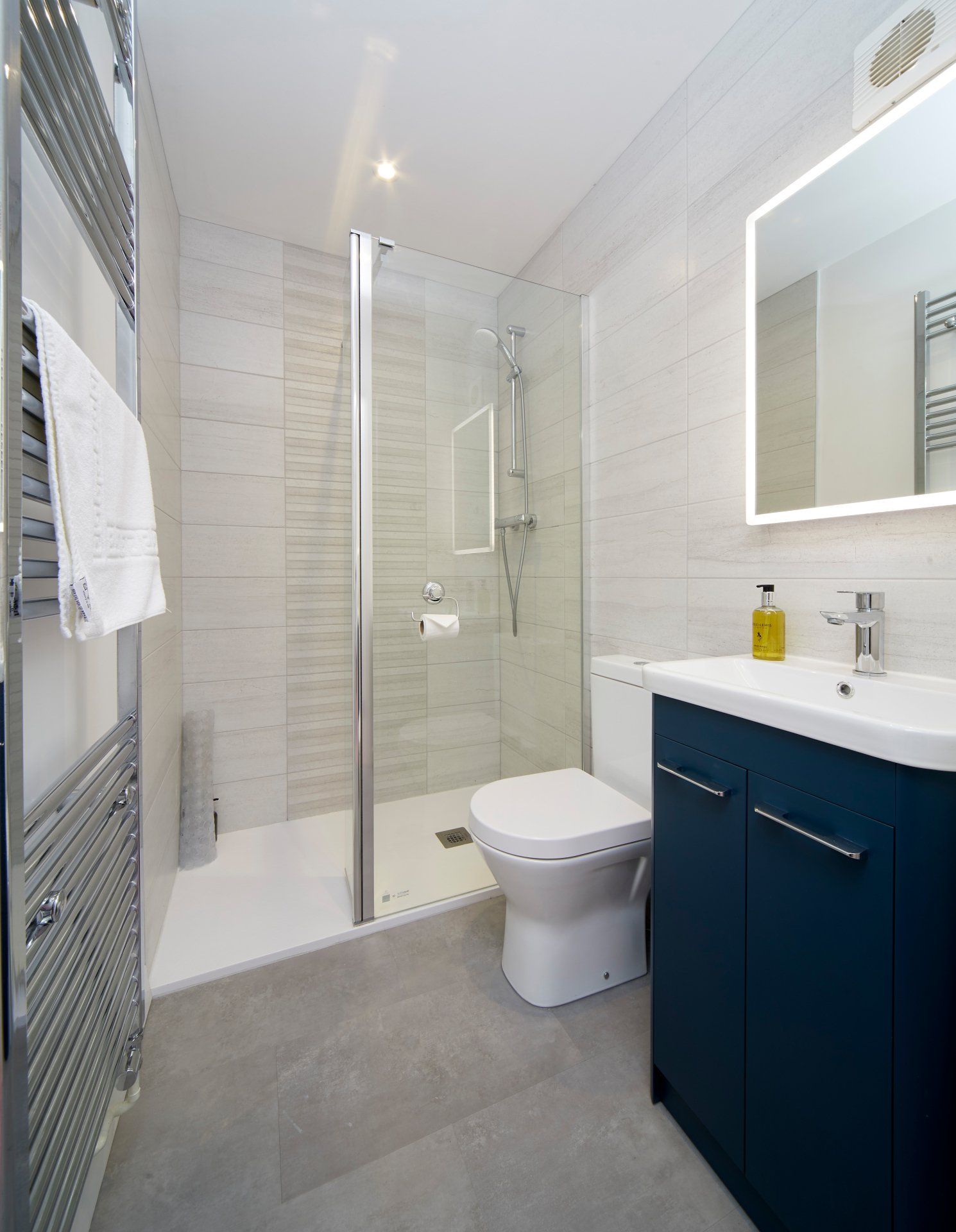 A bathroom with a toilet , sink , mirror and walk in shower.