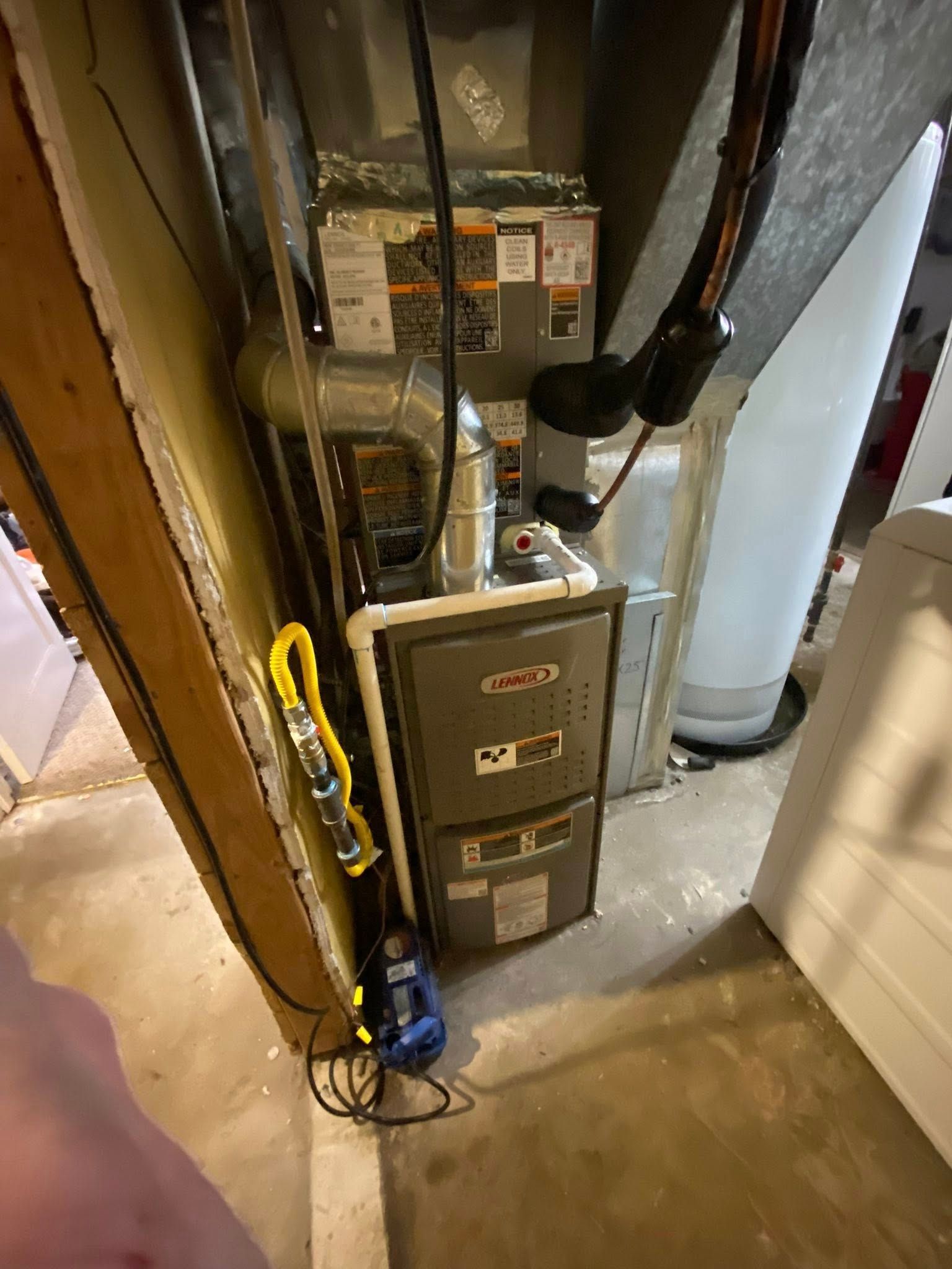 Groulx Mechanical - A furnace is sitting in a basement next to a water heater.