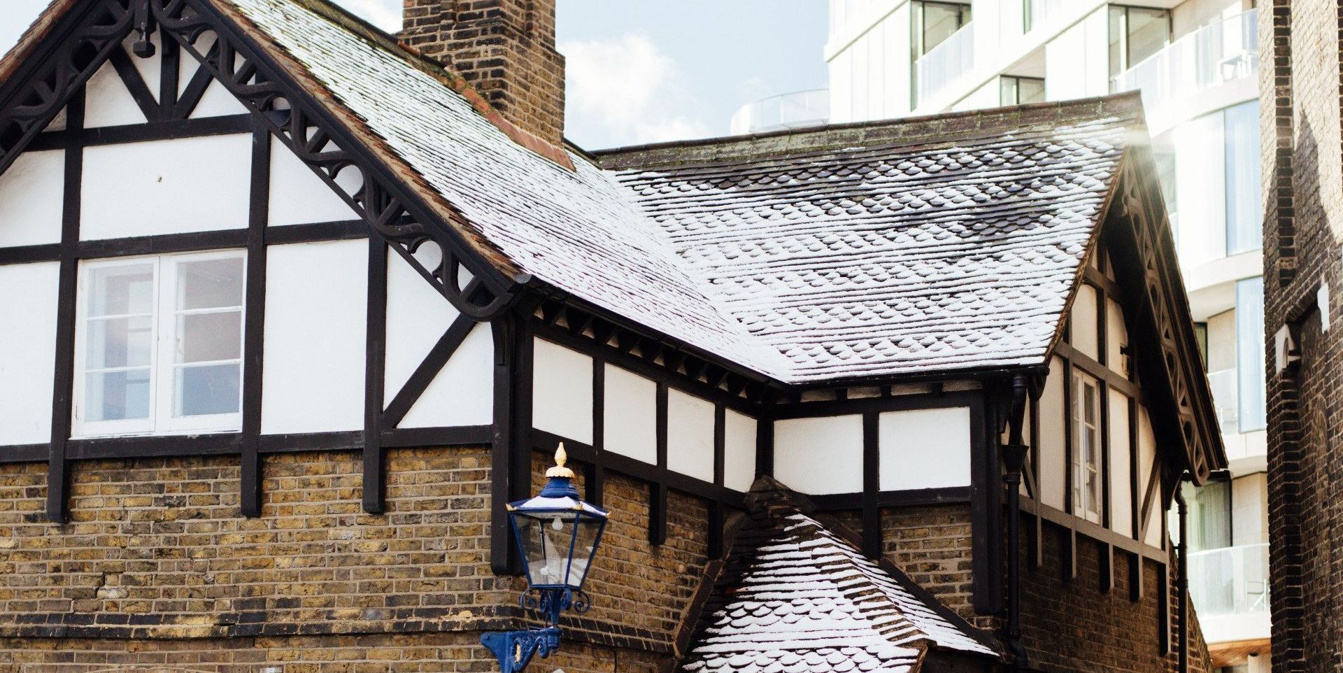 a brick building with a snowy roof and a lamp post in front of it .