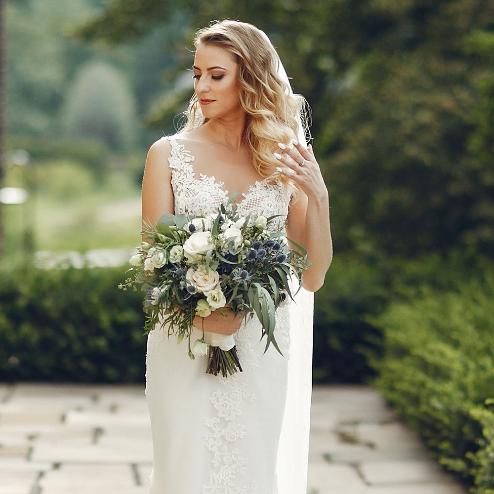 A bride in a wedding dress is holding a bouquet of flowers.