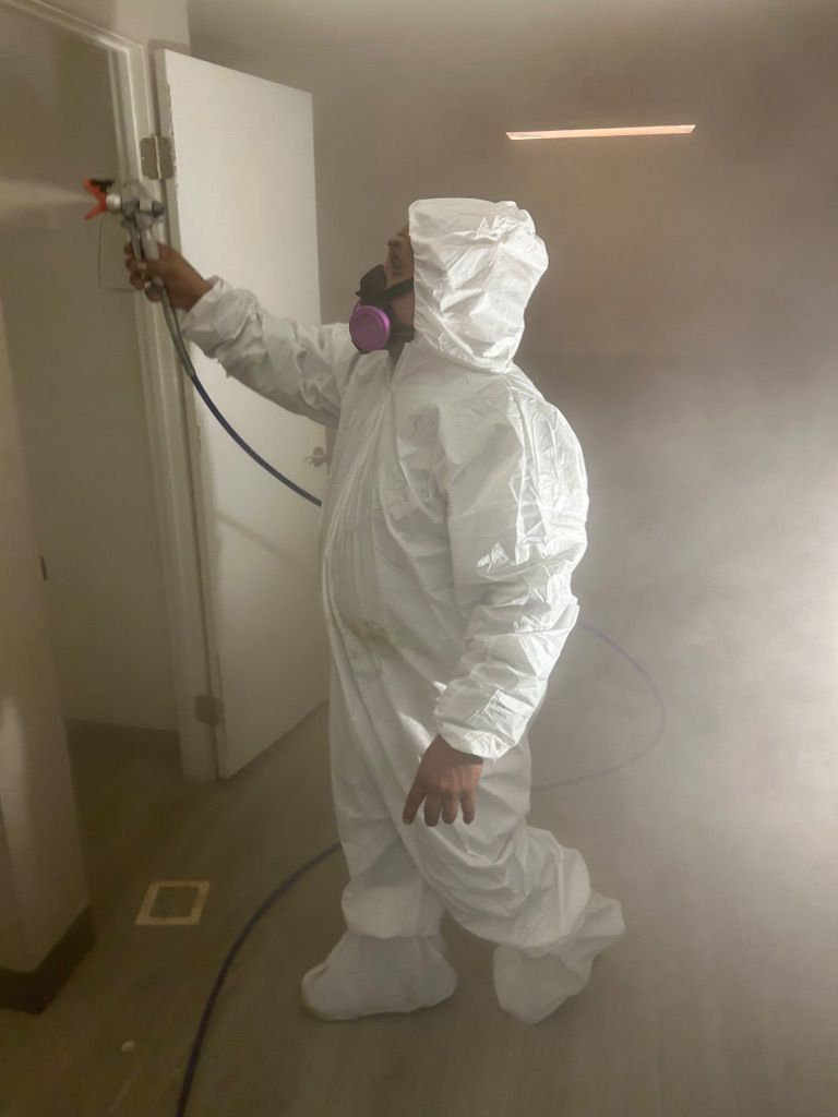 Person in protective suit spraying disinfectant inside a room. Biohazard Service by HRS.
