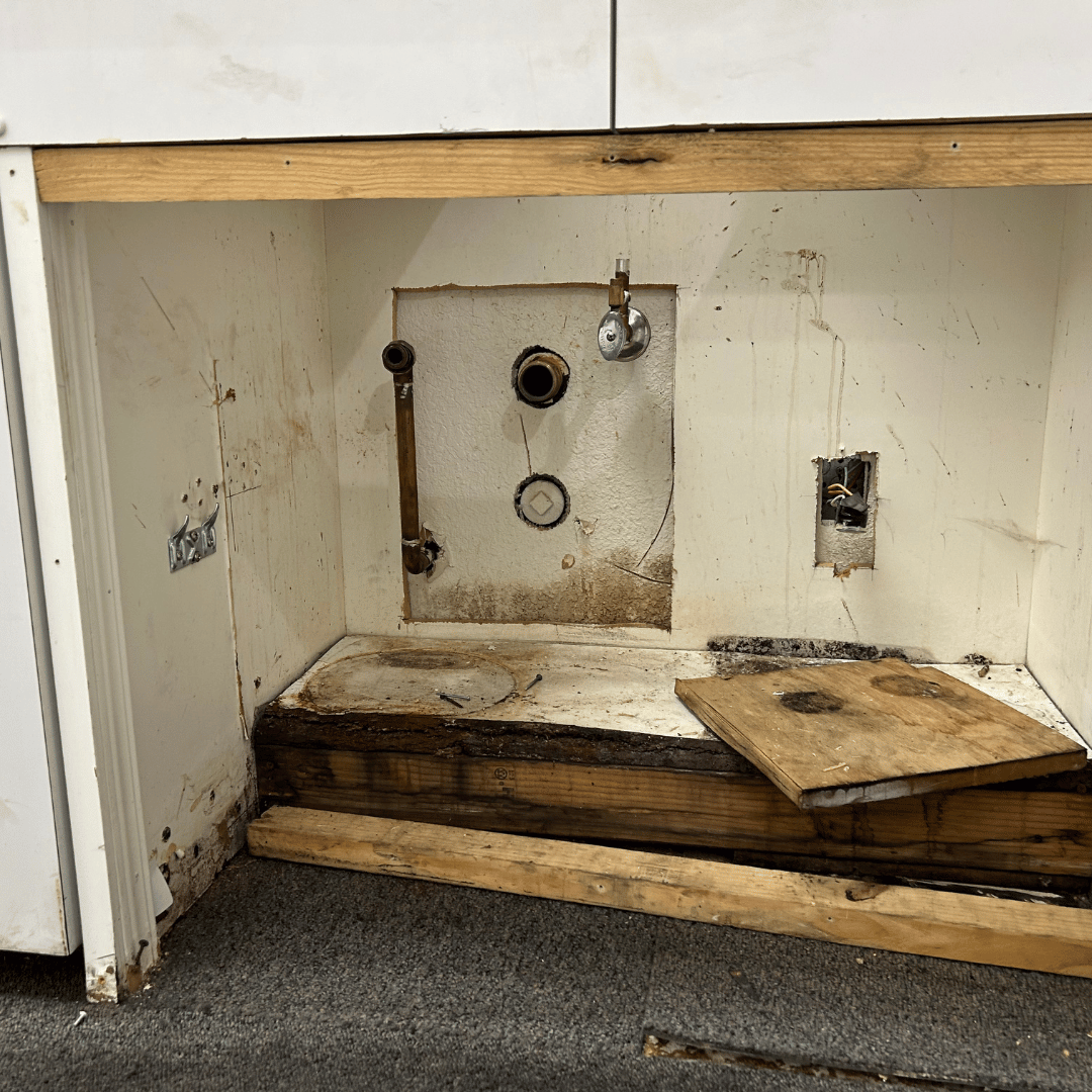 Open cabinet with exposed plumbing, water stains, and damaged wood - HRS Restoration Services in Littleton, CO.